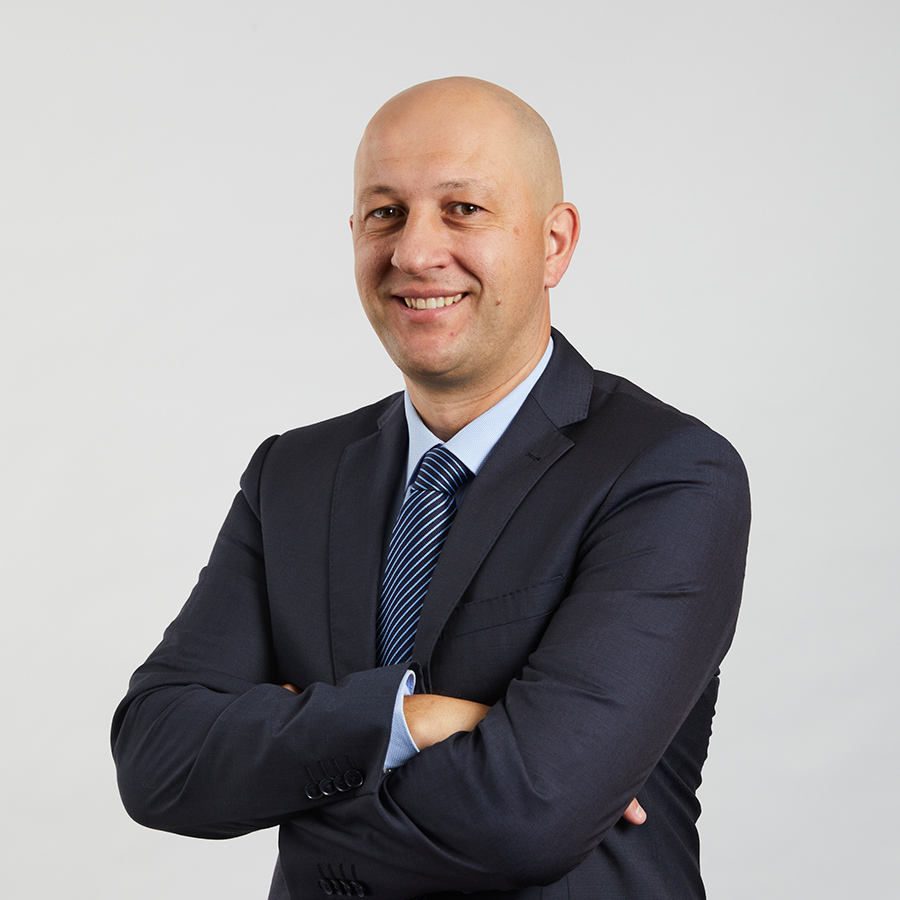 a man wearing a suit and tie smiling at the camera