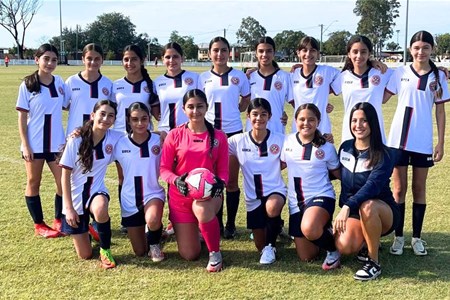 a group of people posing for a photo in front of a football field