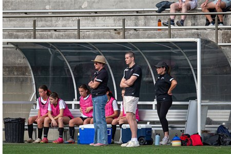 a group of people standing in front of a fence