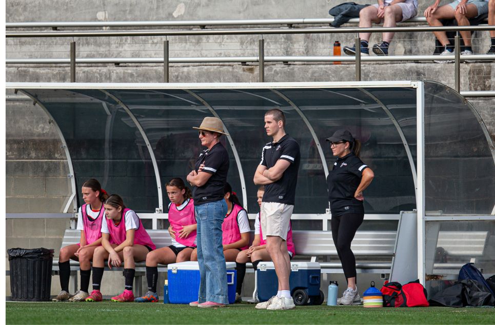 a group of people standing in front of a fence