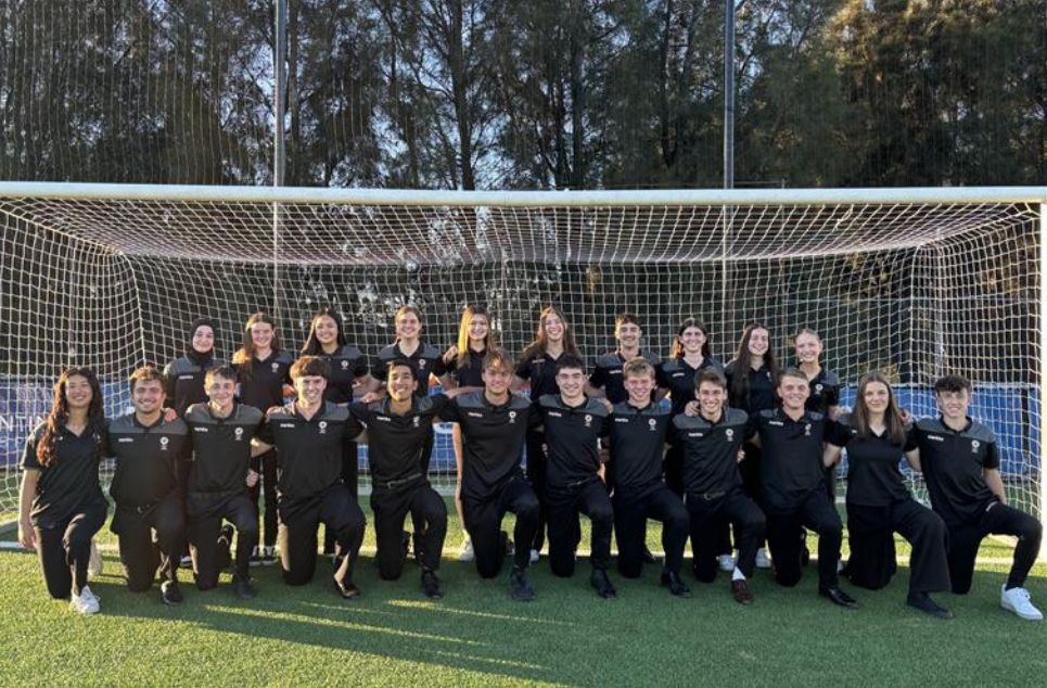 a group of people posing for a photo in front of a fence