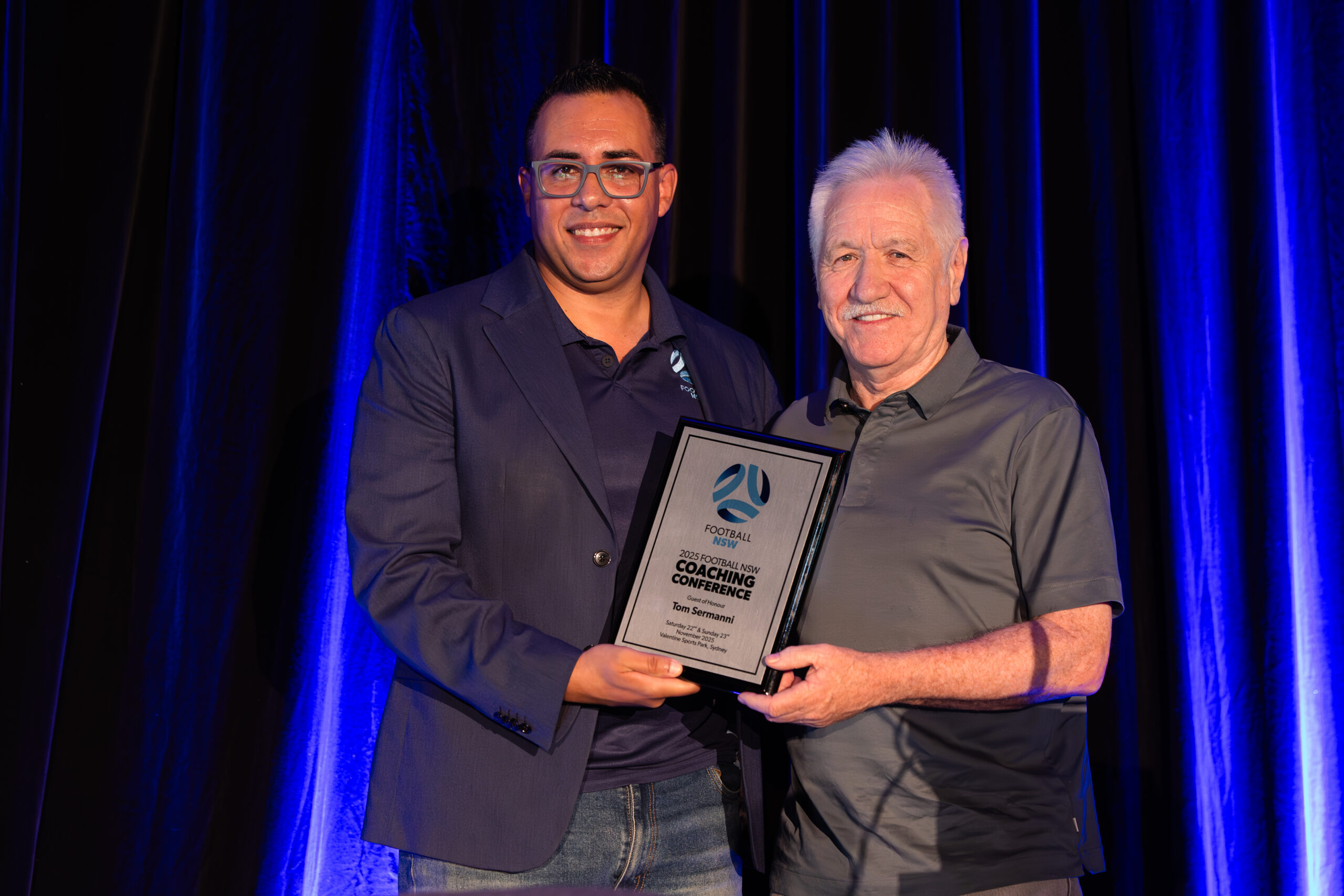 a man standing on a stage in front of a curtain