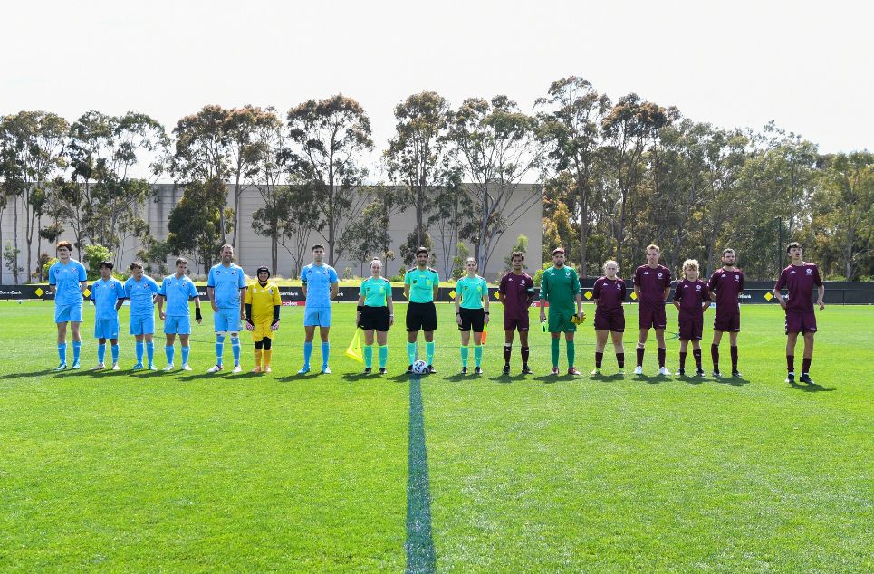 a group of people standing on top of a grass covered field