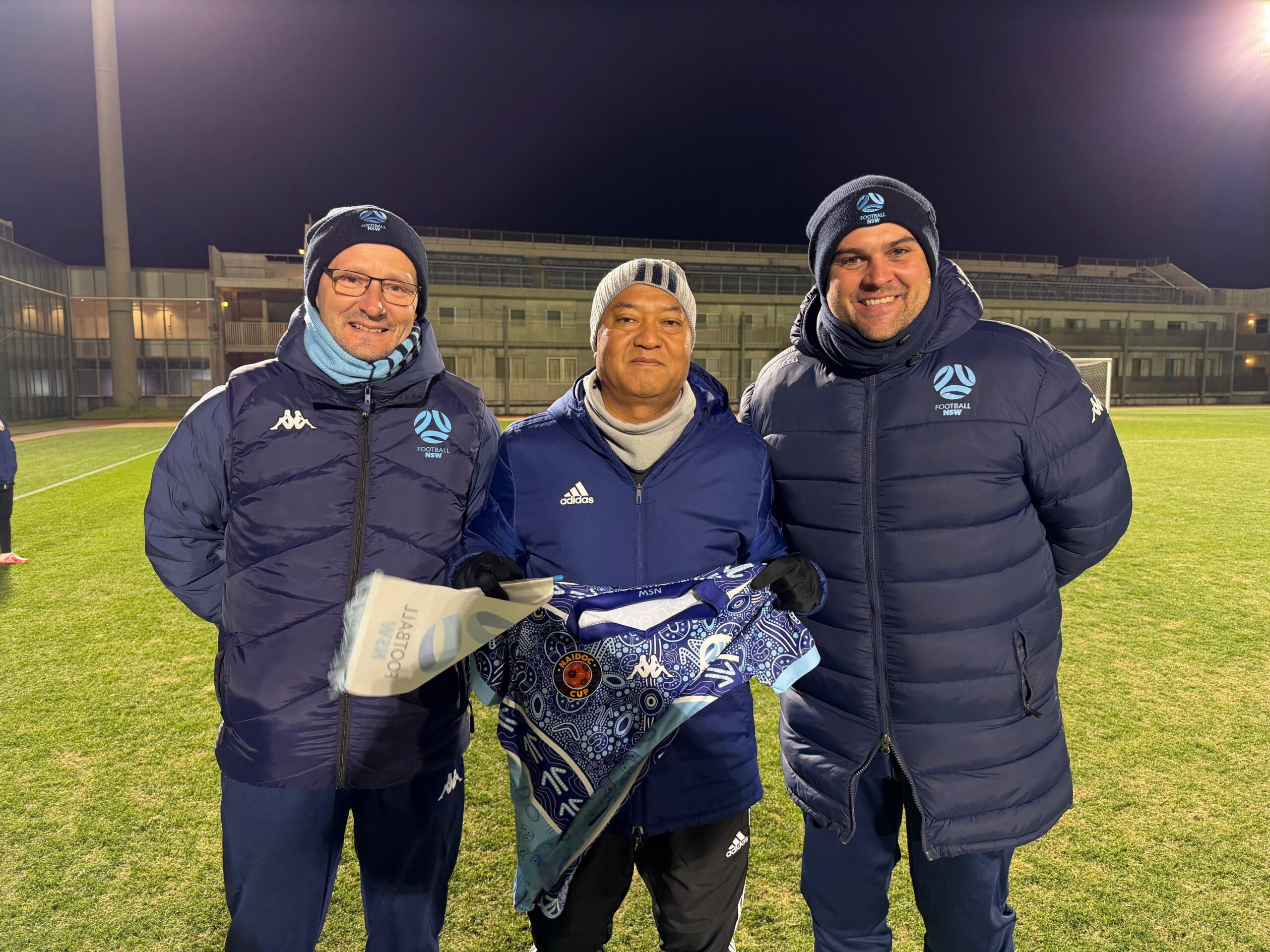 a group of people standing in a grass field posing for the camera