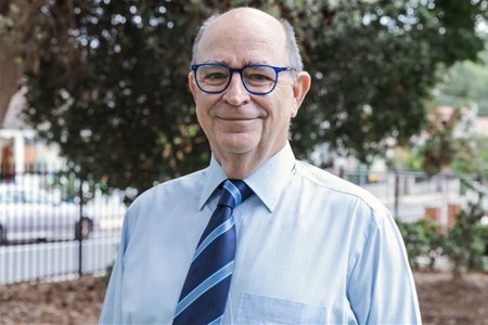 a man wearing glasses and smiling at the camera