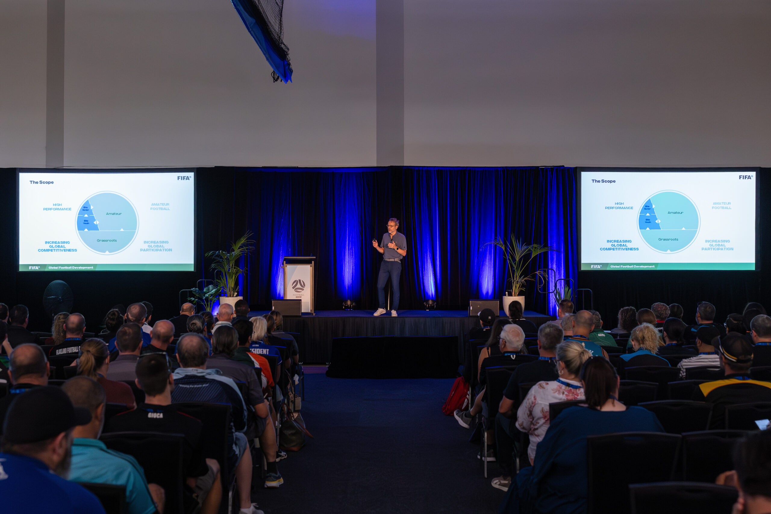 a group of people sitting in front of a crowd of people watching television