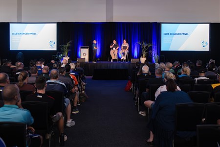 a group of people sitting in front of a crowd of people watching television