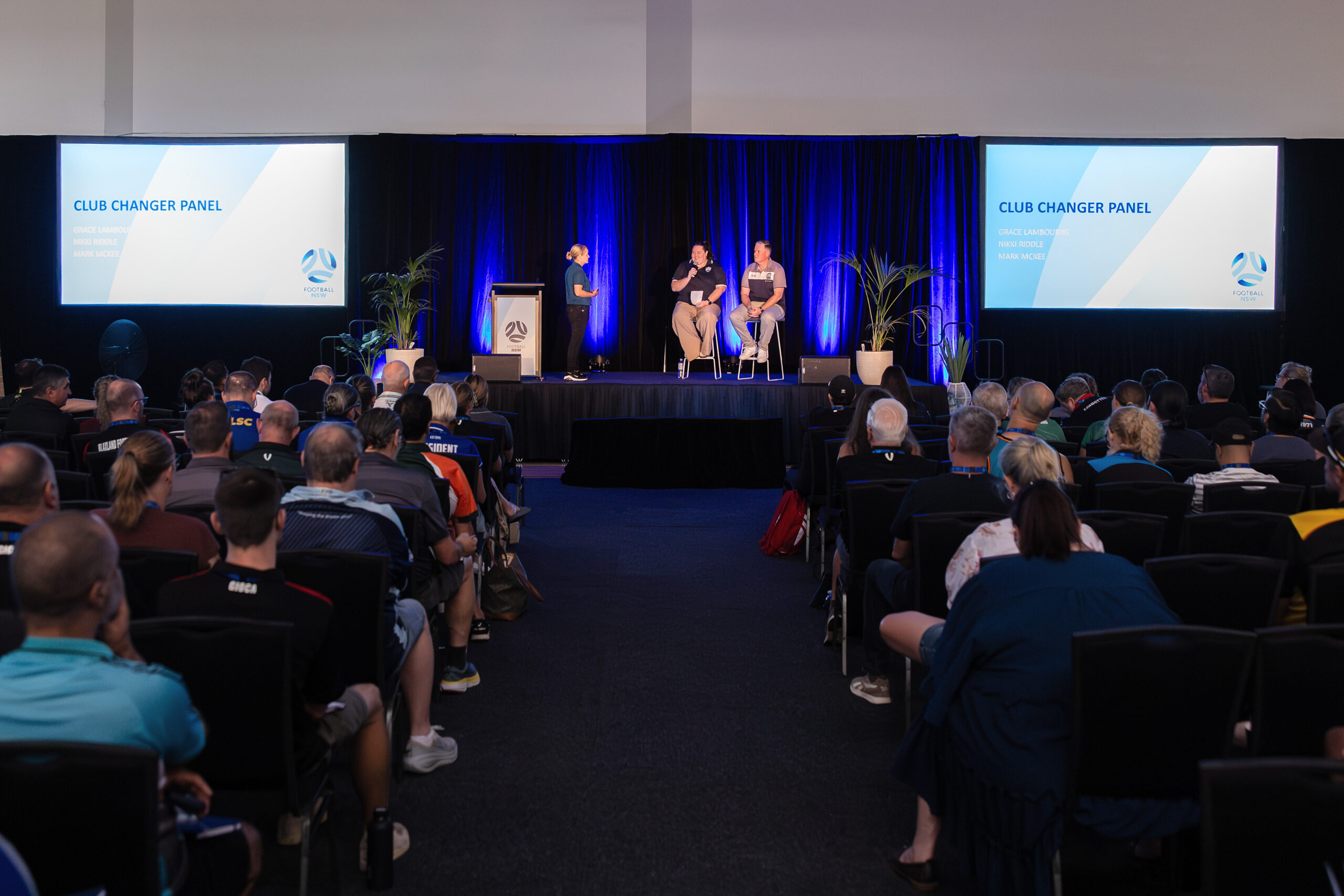 a group of people sitting in front of a crowd of people watching television
