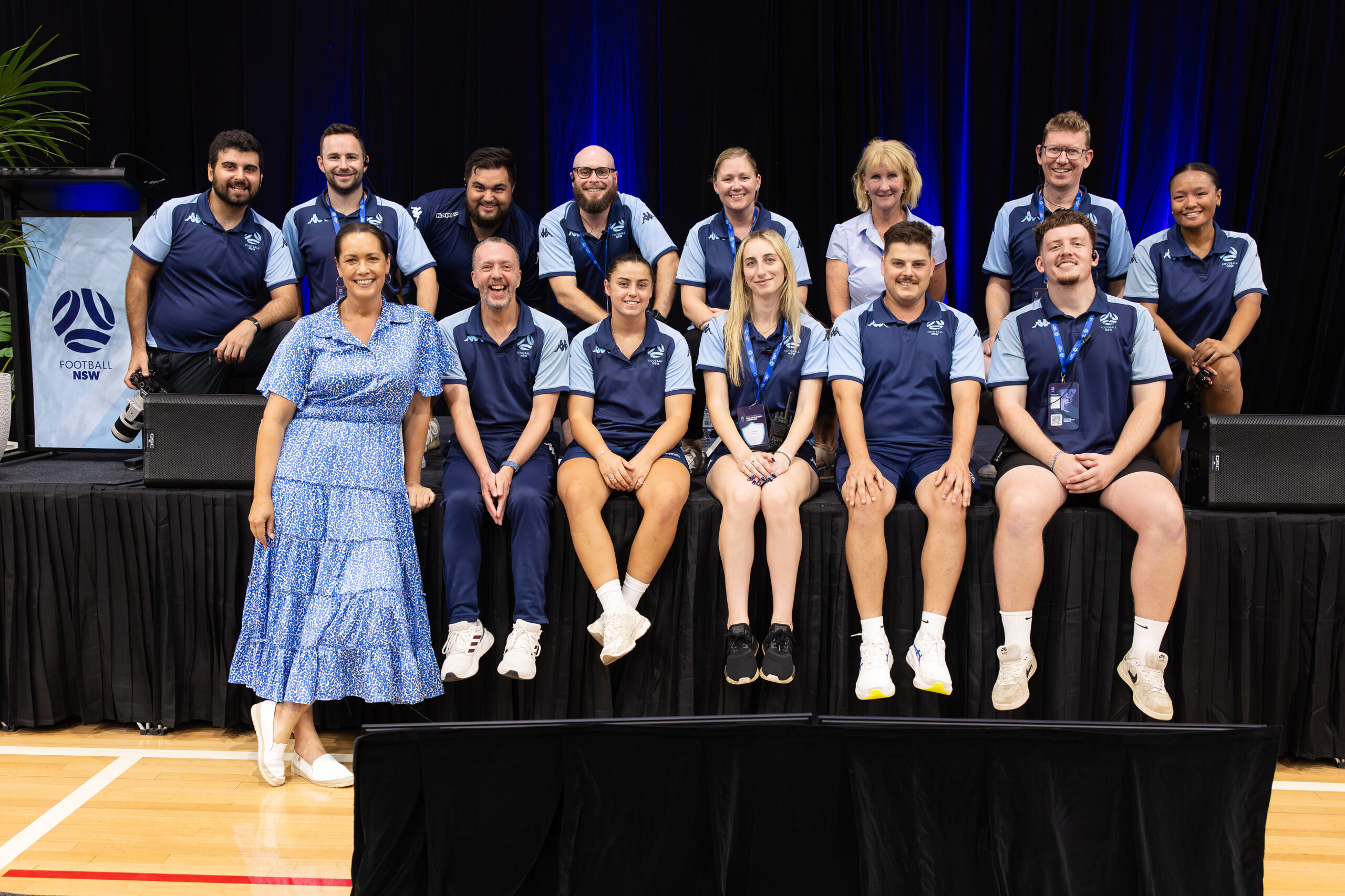 a group of people posing for a photo in front of a stage