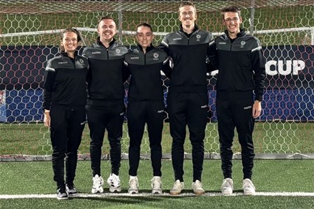 a group of people standing in a grass field posing for the camera